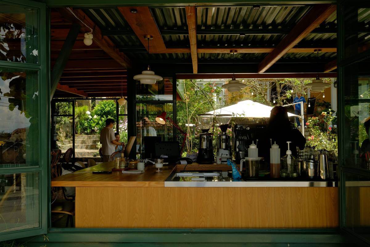 Close-up of tropical bar furniture design showing hand-carved details on a solid acacia bar front with copper inlays and natural fiber barstools